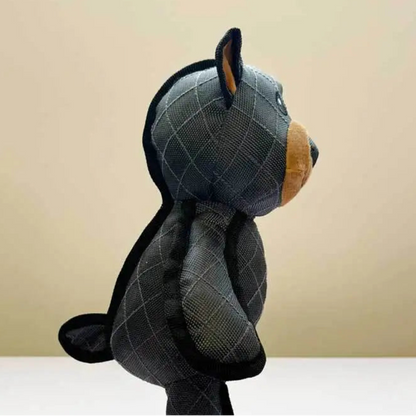 Plush toy resembling a bear fot a dog with a checkered pattern on a beige background