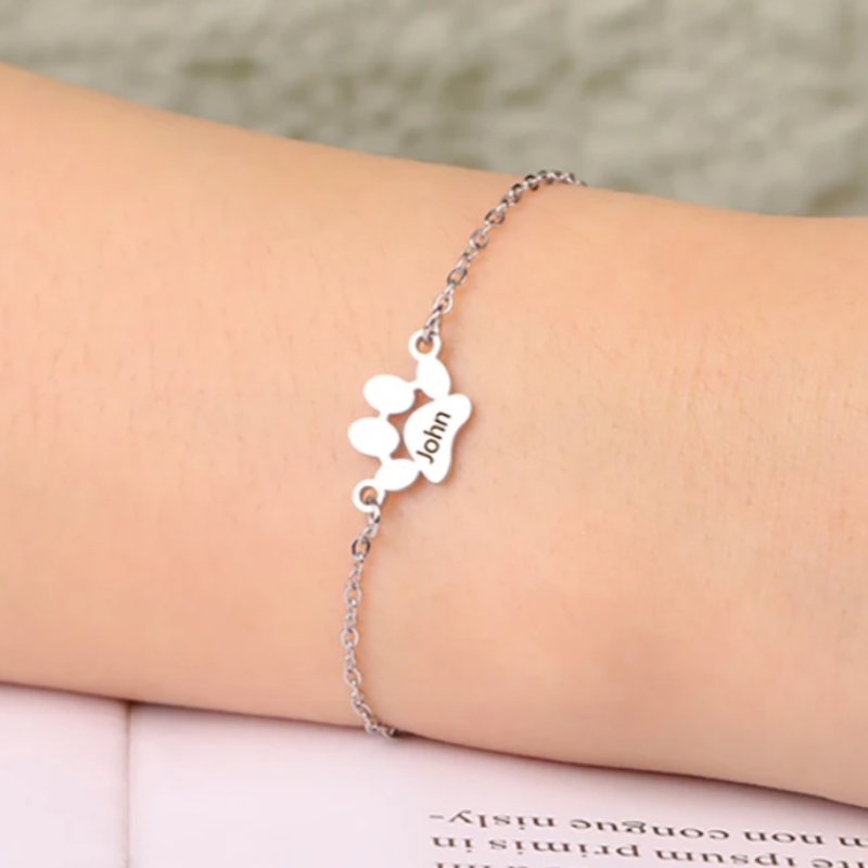 Silver bracelet with paw print design on a wrist